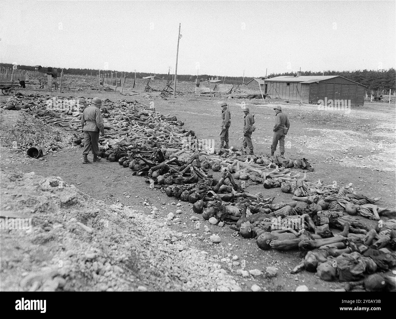 American soldiers in Kaufering IV look at the bodies of prisoners killed by the SS prior to the arrival of U.S. forces. Kaufering was a sub-camp of Dachau concentration camp. Dachau was the first nazi concentration camp, opening on 22 March 1933 (just 7 weeks after Hitler came to power). Although it was a forced labour camp and there were no gas chambers there, brutality and violent punishments were the norm. There were 32000 documented deaths there and many thousands more undocumented. The main camp (Dachau had 100 sub-camps) was liberated by the US Army on 29th April 1945. Stock Photo