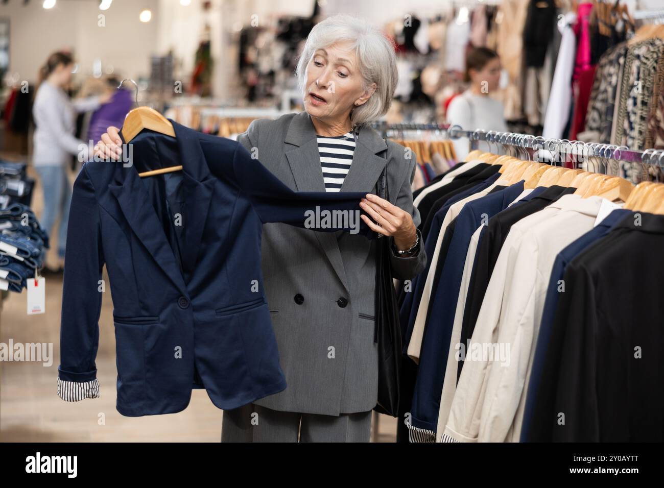 Old woman choosing convenient blazer in clothing store Stock Photo - Alamy