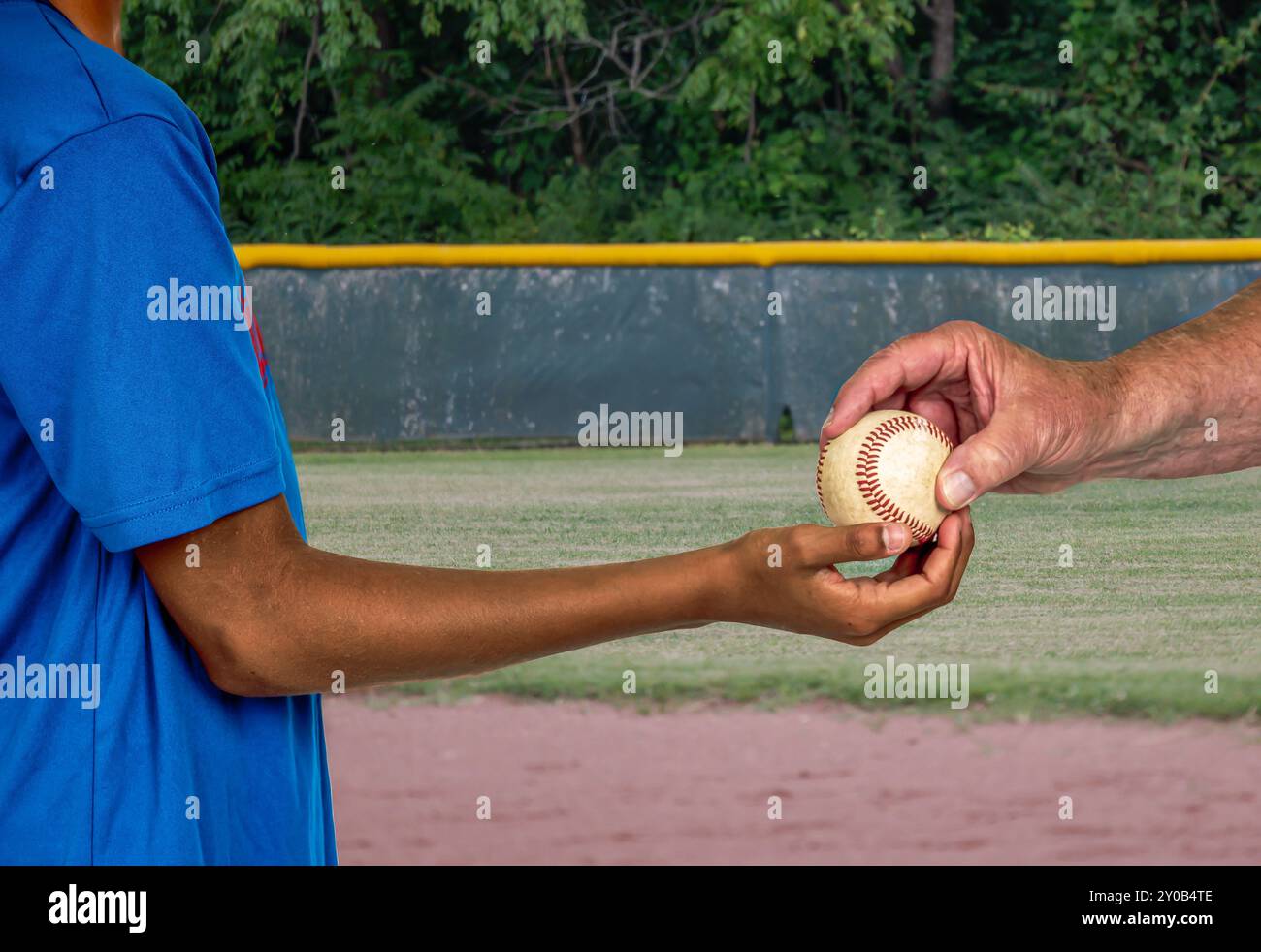 Adult umpire hands game ball to youth baseball pitcher Stock Photo