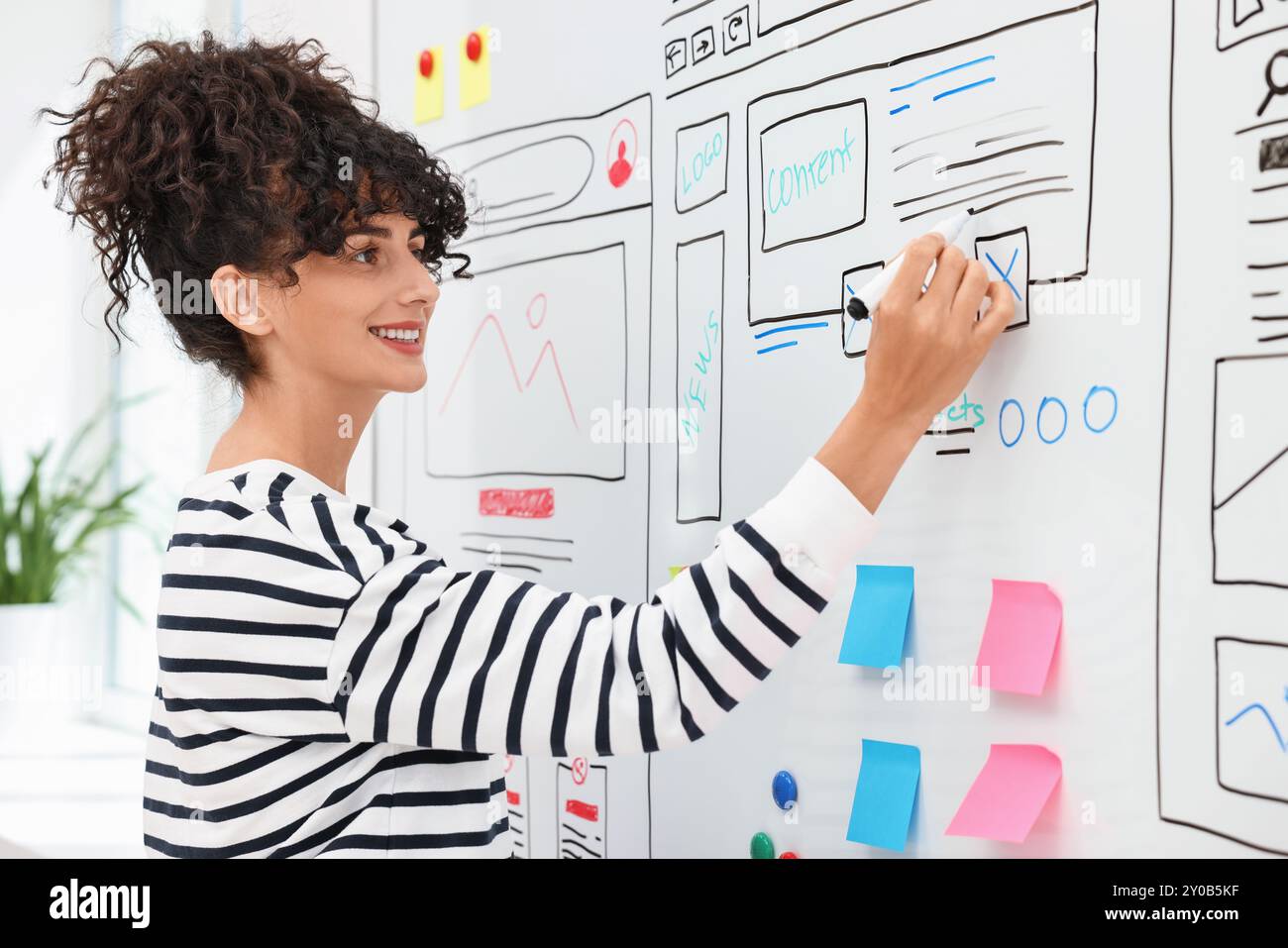 Developing UI design. Woman drawing website wireframe on whiteboard indoors Stock Photo