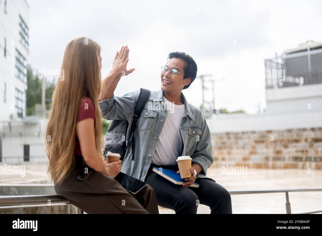 A happy, smart young Asian male college student is giving a high five ...