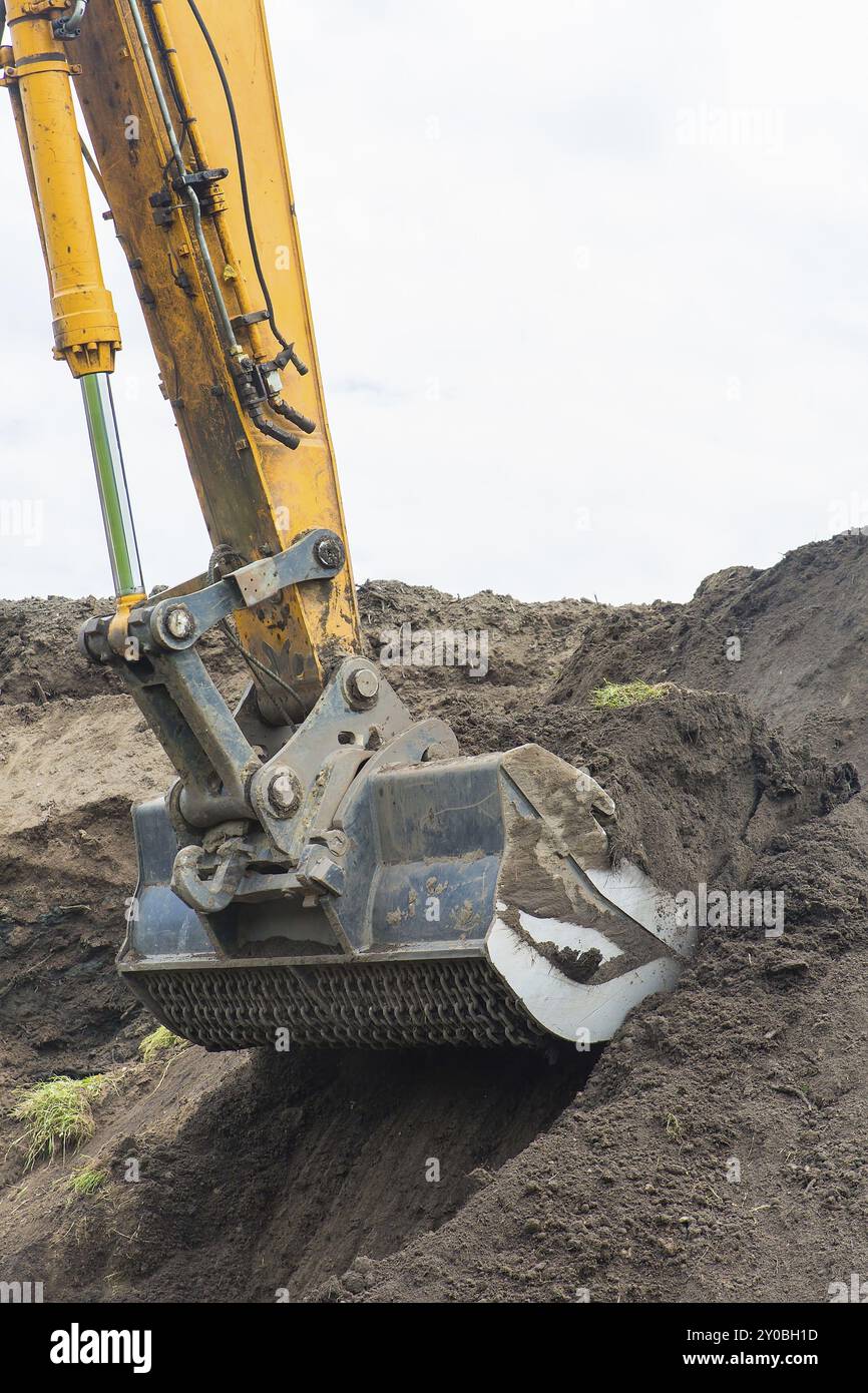 Excavator digs up ground from sandy hill Stock Photo