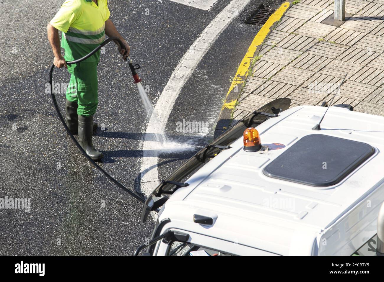 Worker cleaning the road and street sidewalk with high pressure water. Public maintenance concept Stock Photo