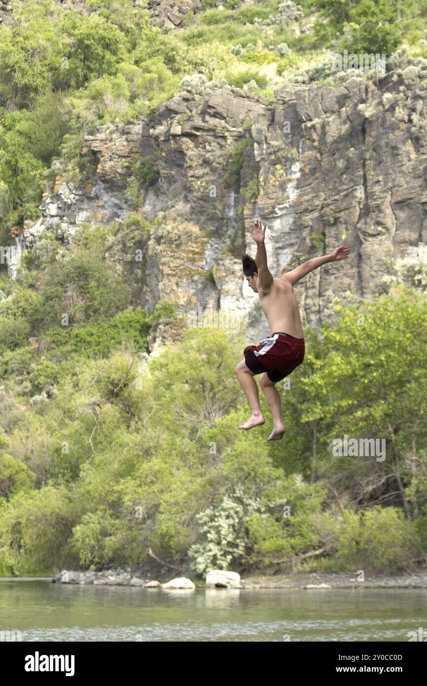 A young man is jumping off a cliff into the water below in Twin Falls ...
