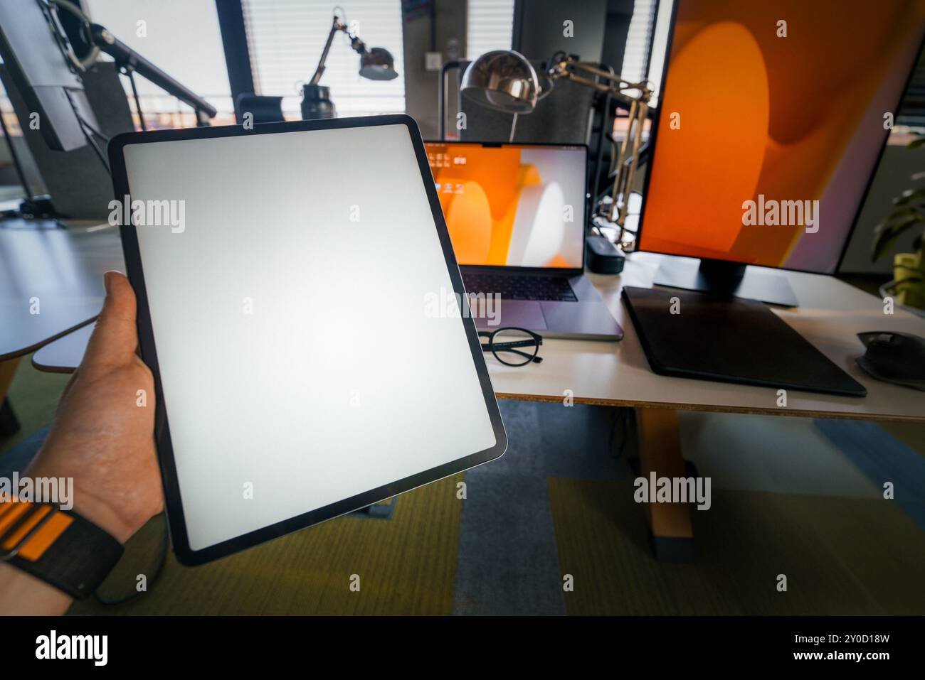 hand holding empty screen tablet mockup office interior Stock Photo