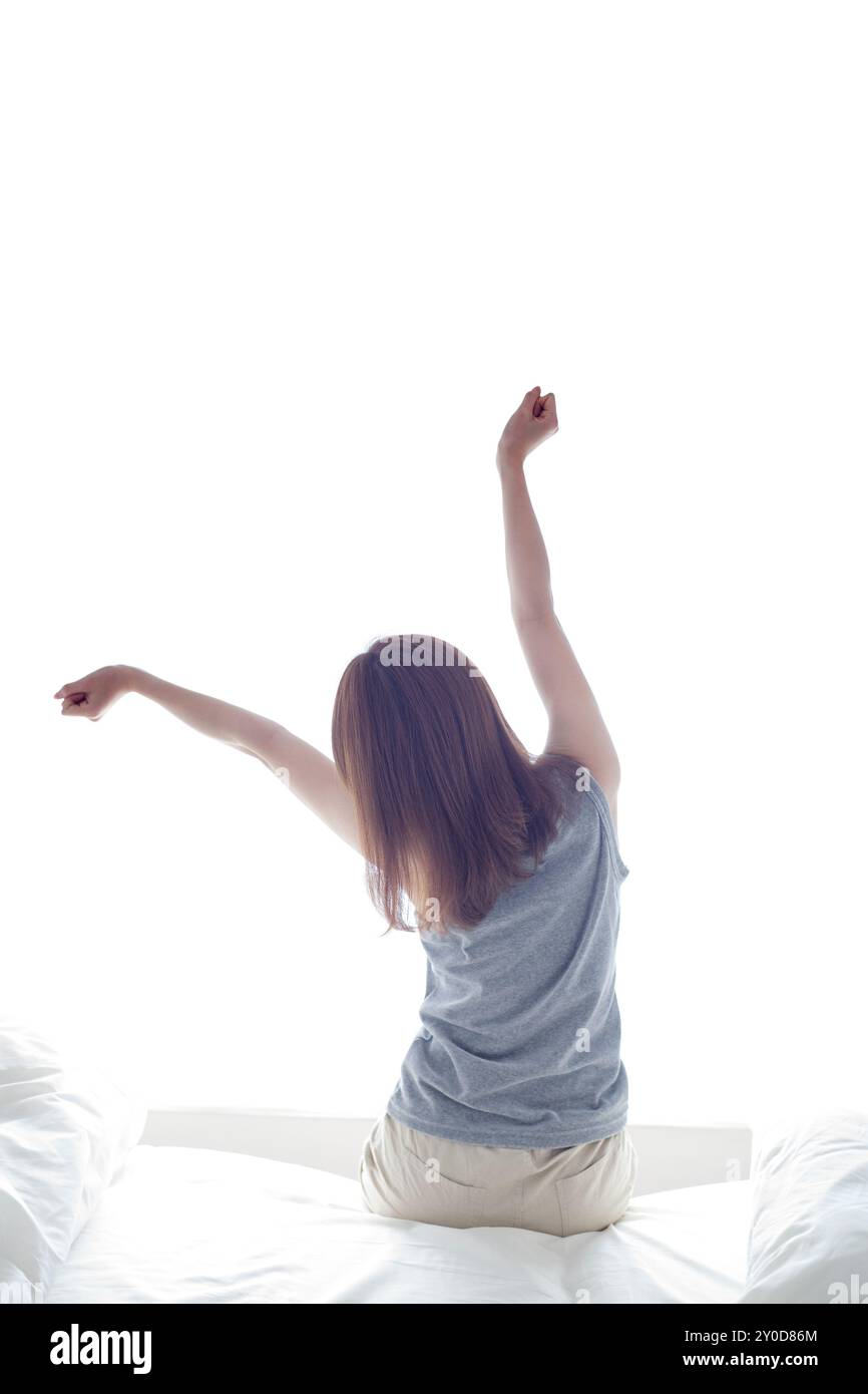 Back view of a woman stretching out her arms sitting on a bed Stock ...