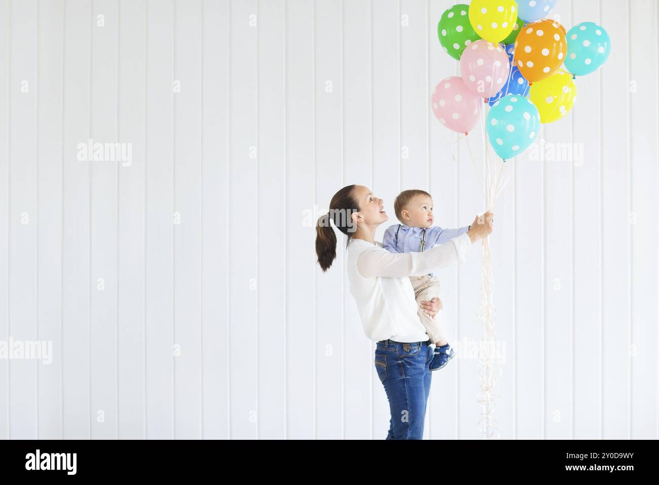 Little boy with his mom holding a large bunch of colored balloons Stock Photo