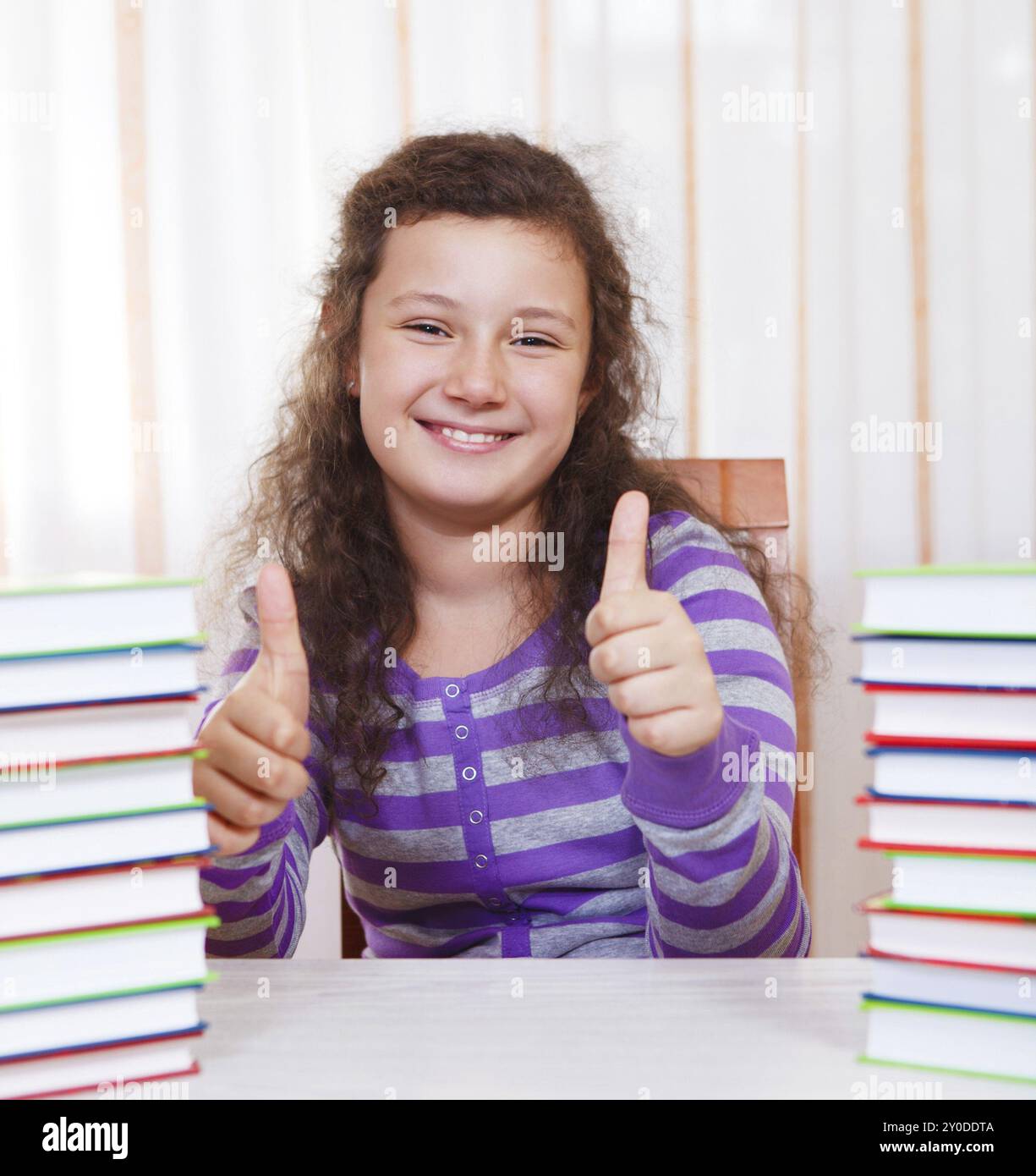 Little brunette smiling girl with pile of books Stock Photo - Alamy