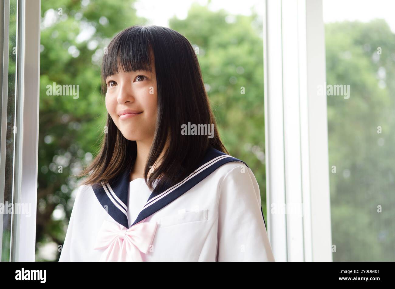 A smiling high school girl in uniform by a window Stock Photo - Alamy