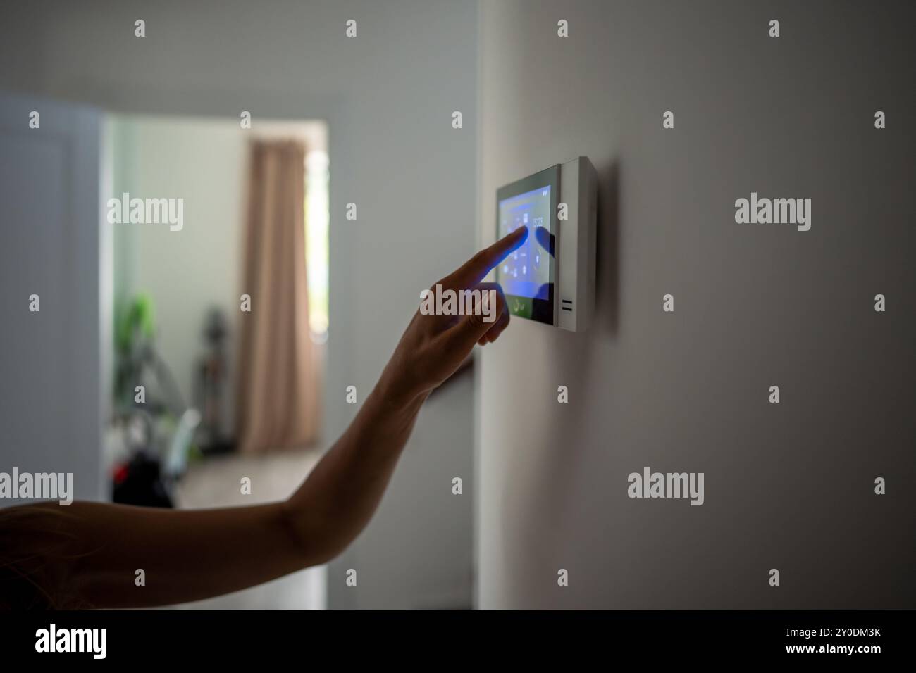 Closeup hand using smart home panel, touching screen with connected appliances device on wall. Stock Photo