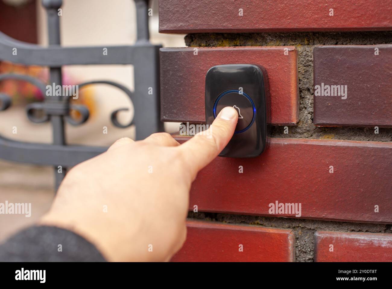 Hand Pressing Doorbell on Red Brick Wall Stock Photo