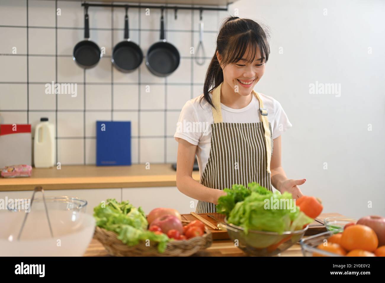 Smiling young asian woman wearing apron preparing a fresh and healthy ...