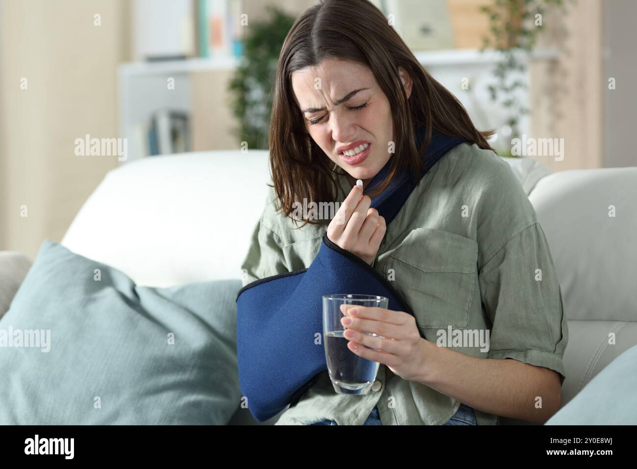 Stressed convalescent woman taking painkiller pill complaining at home Stock Photo