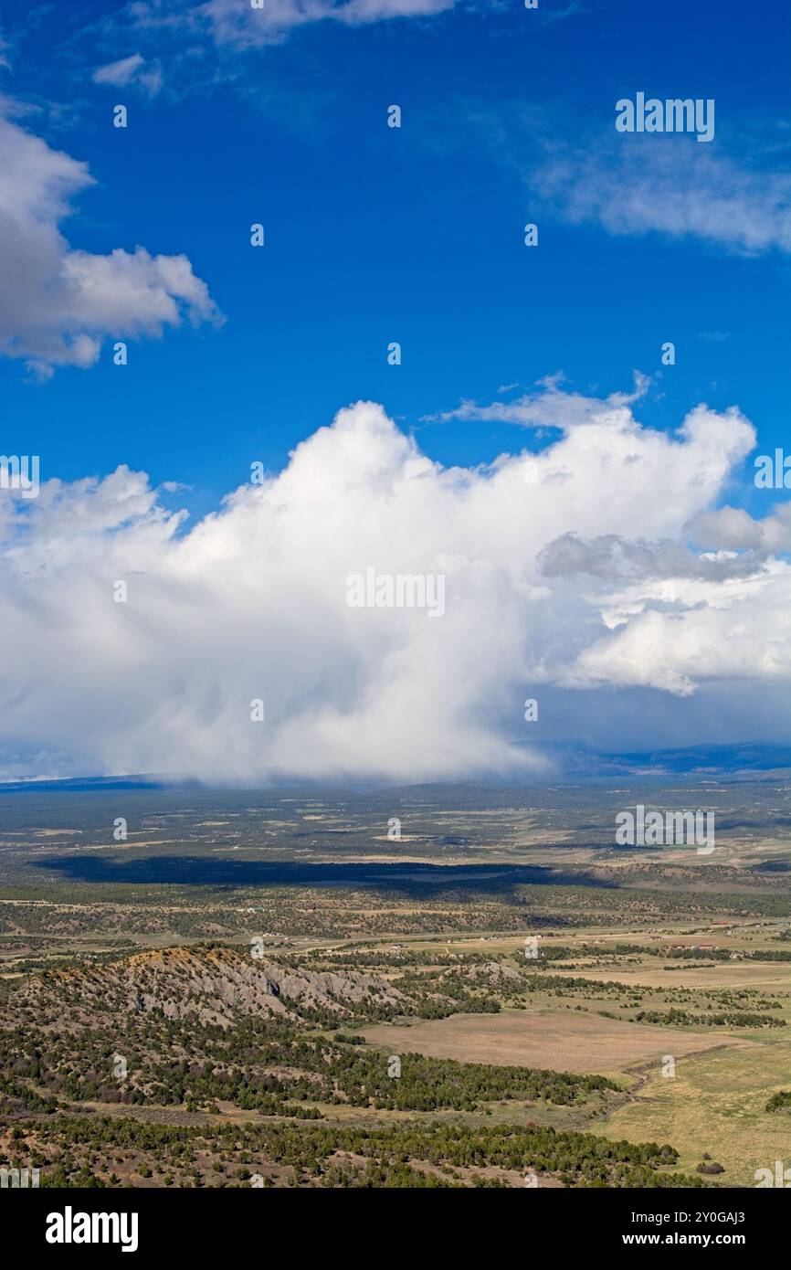 Overview of expansive green plains of Montezuma Valley with passing spring shower from mesa top at Mesa Verde National Park Stock Photo