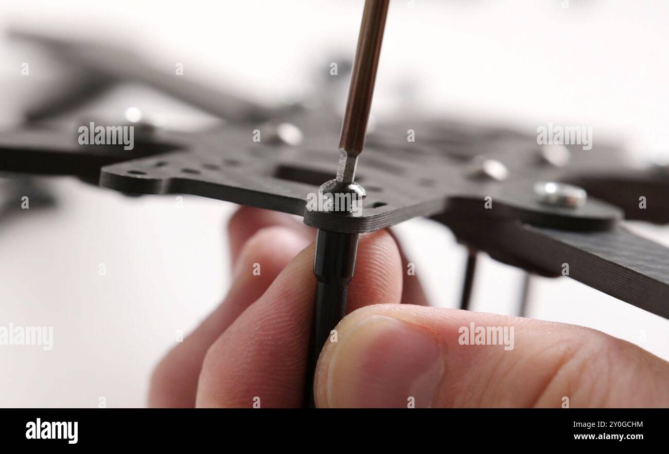 Homemade assembling fpv DIY drone. Tightening a motor screws by screwdriver Stock Photo