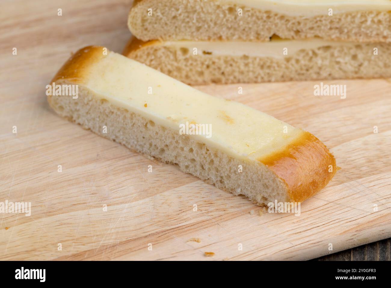 Cut into pieces round bun with creamy sour cream filling, sour cream bun for tea Stock Photo