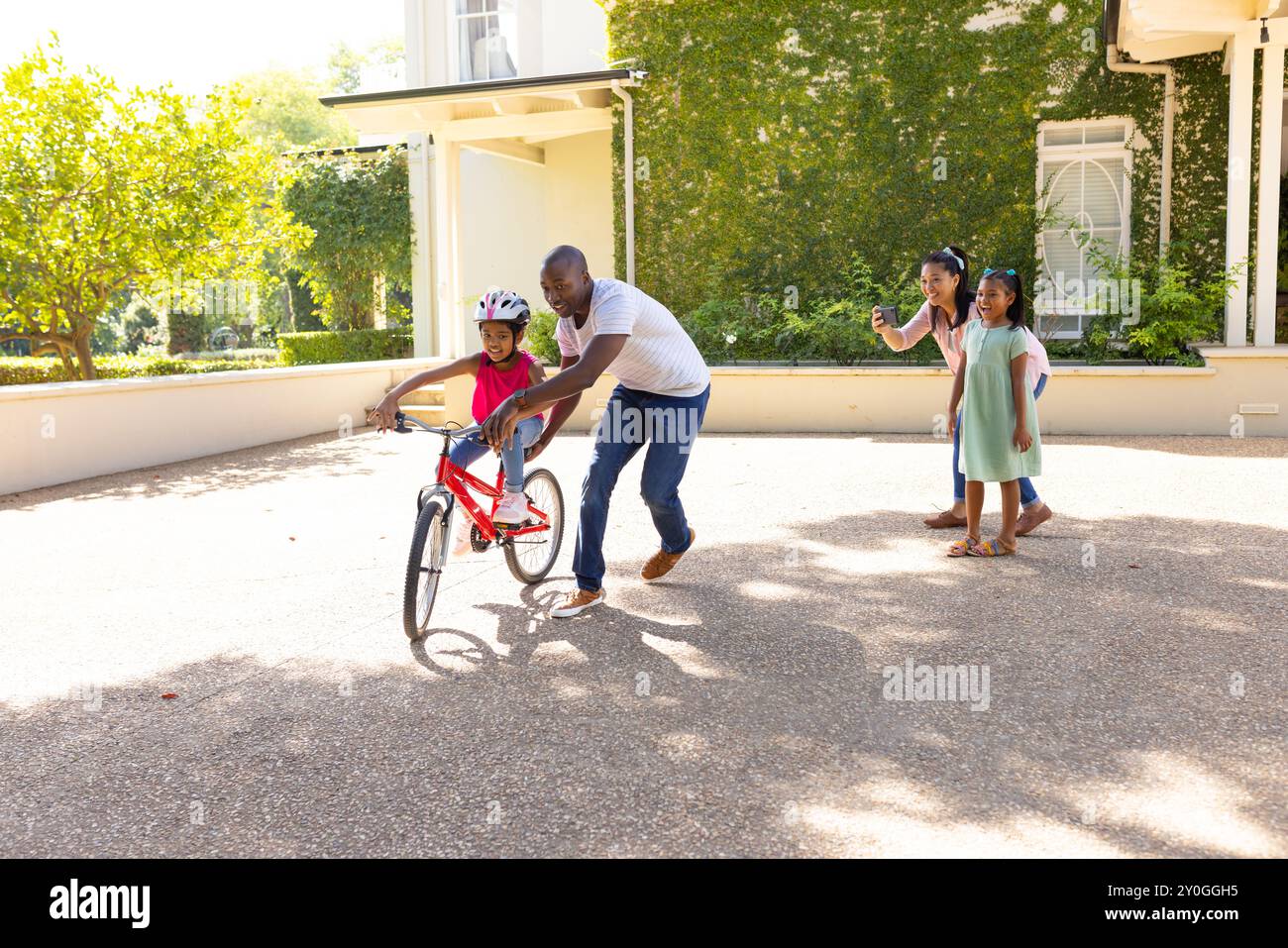 Teaching child to ride bicycle, father supporting while mother and ...