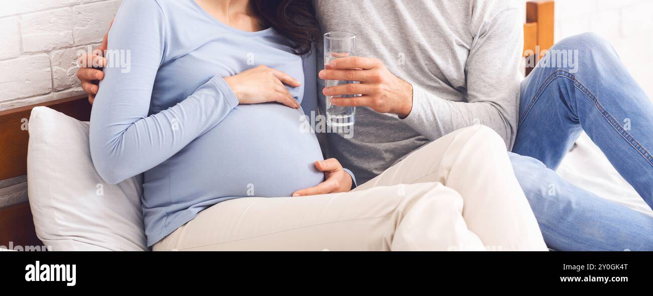 Caring Husband Giving Glass Of Water To His Pregnant Wife Stock Photo