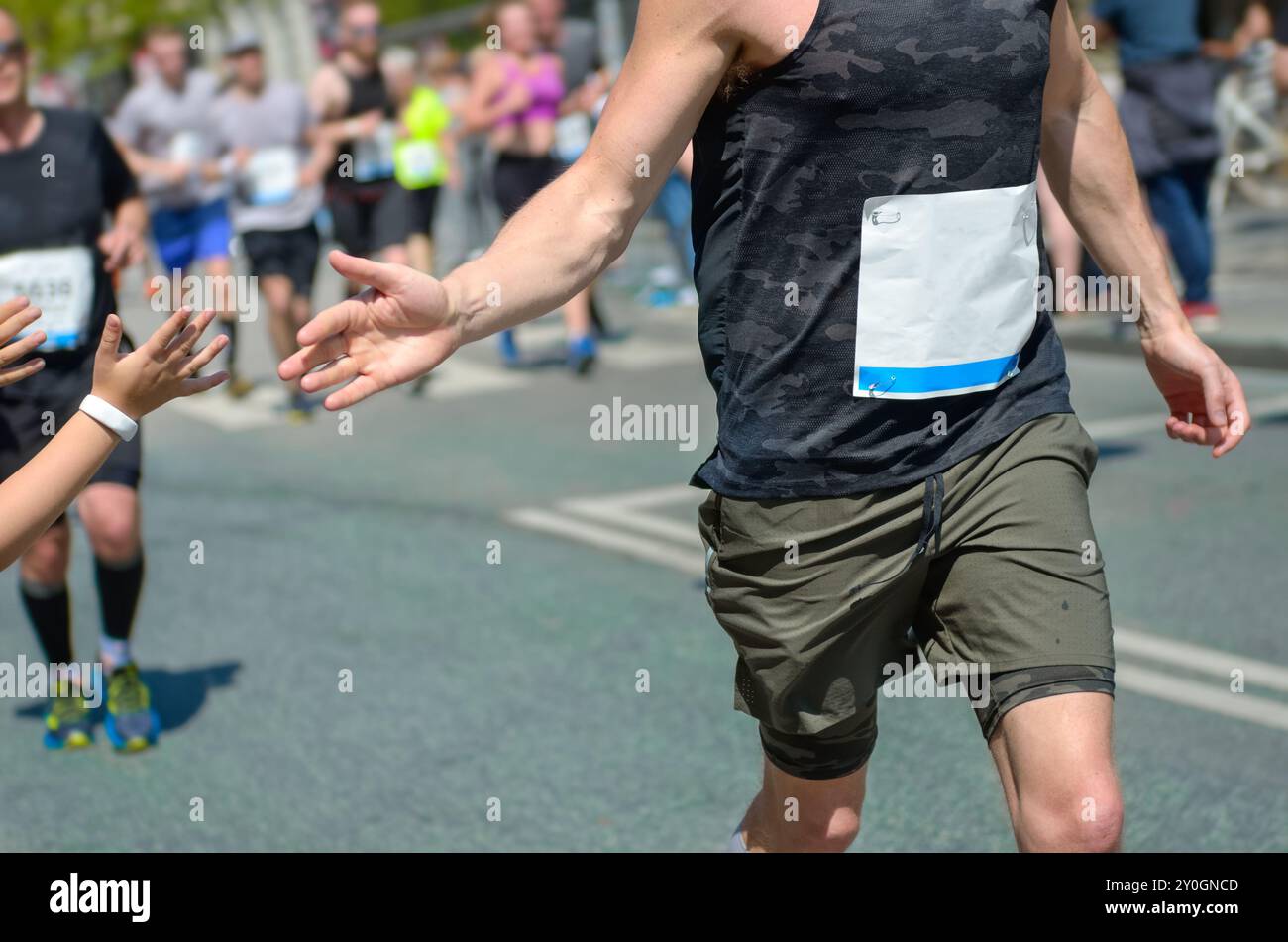 Marathon running race,runners support on road race, child's hand giving ...