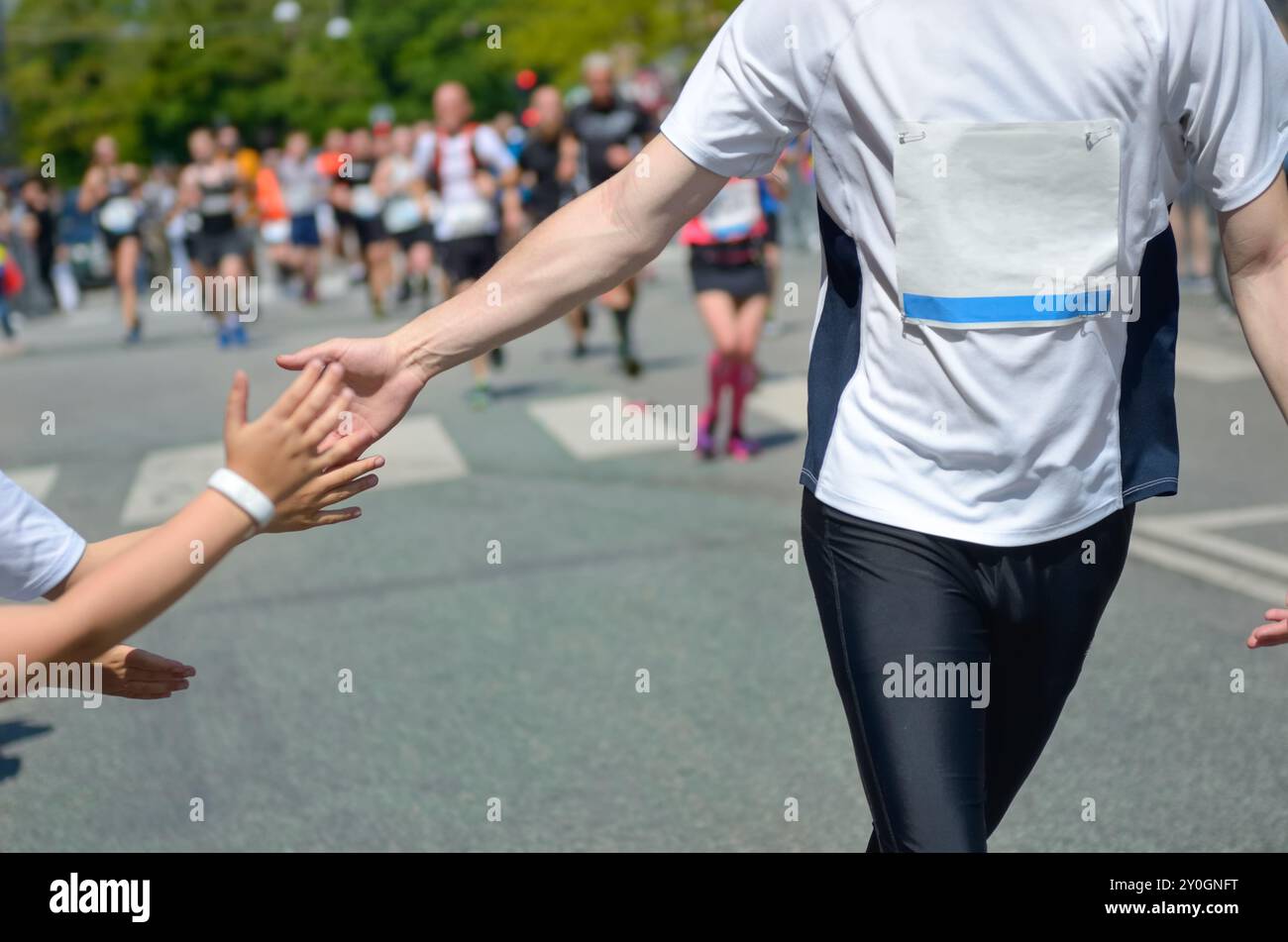Marathon running race,runners support on road race, child's hand giving ...