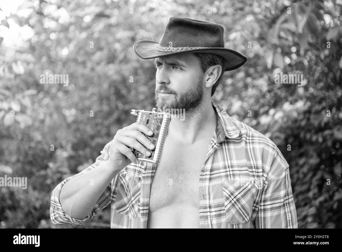 man hold bourbon hipflask outdoor. man with bourbon hipflask wear checkered shirt. Stock Photo