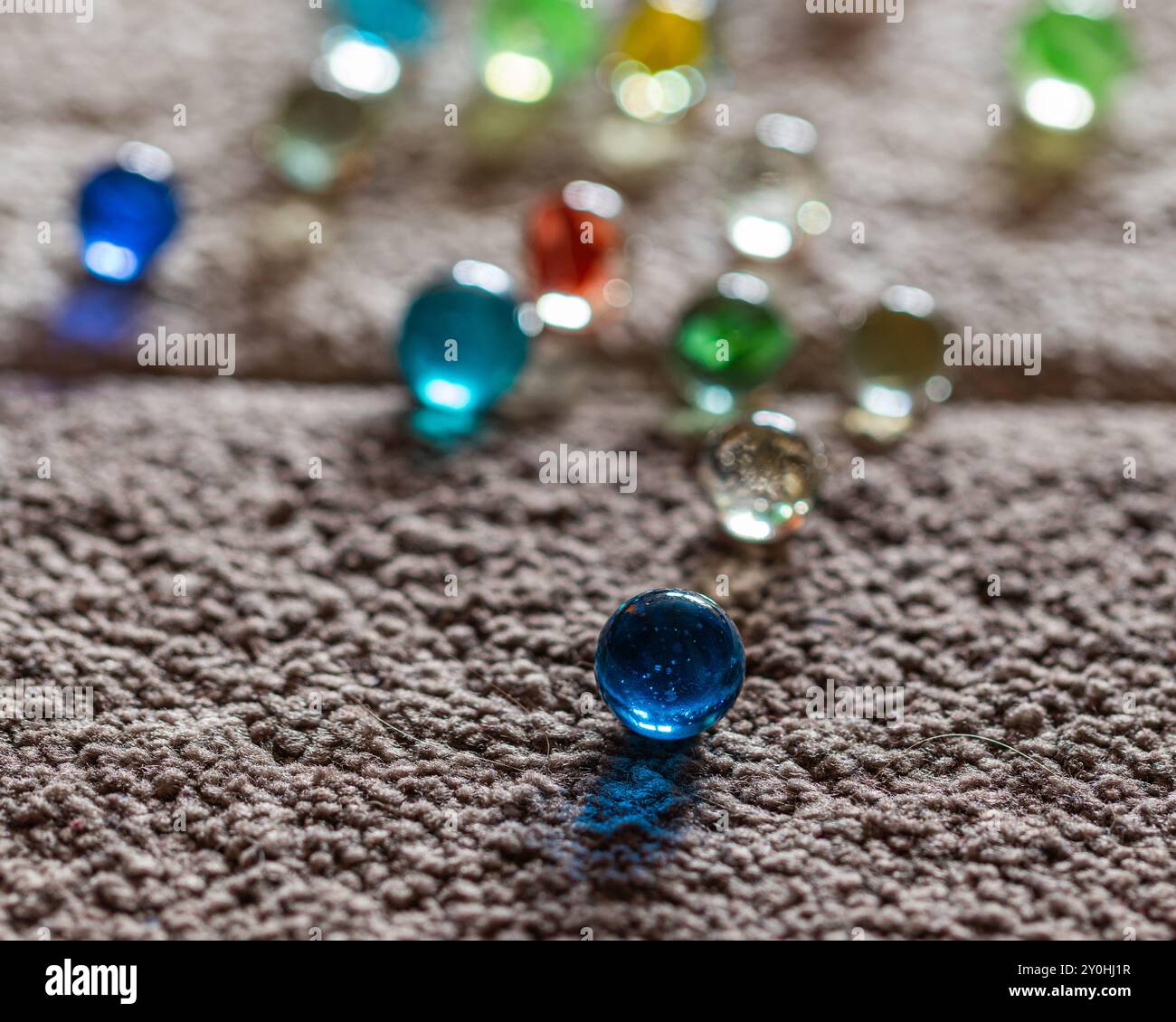 Colorful marbles scattered on a textured carpet, focusing on a singular ...