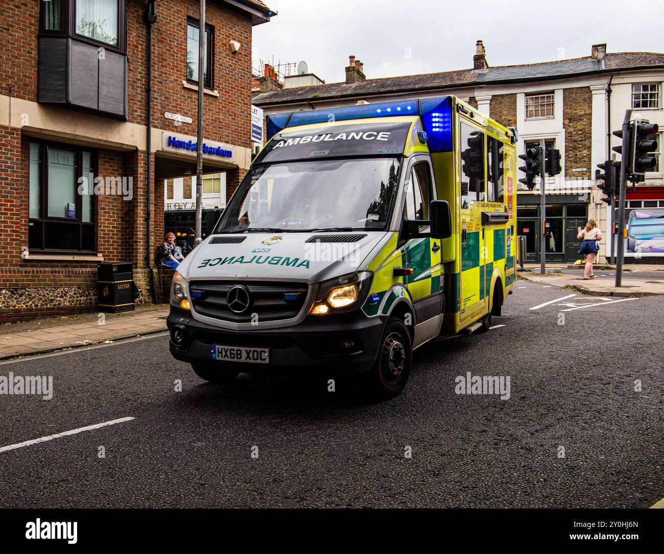 A yellow and green ambulance is driving down a city street, offering emergency medical services in an urban environment. Stock Photo