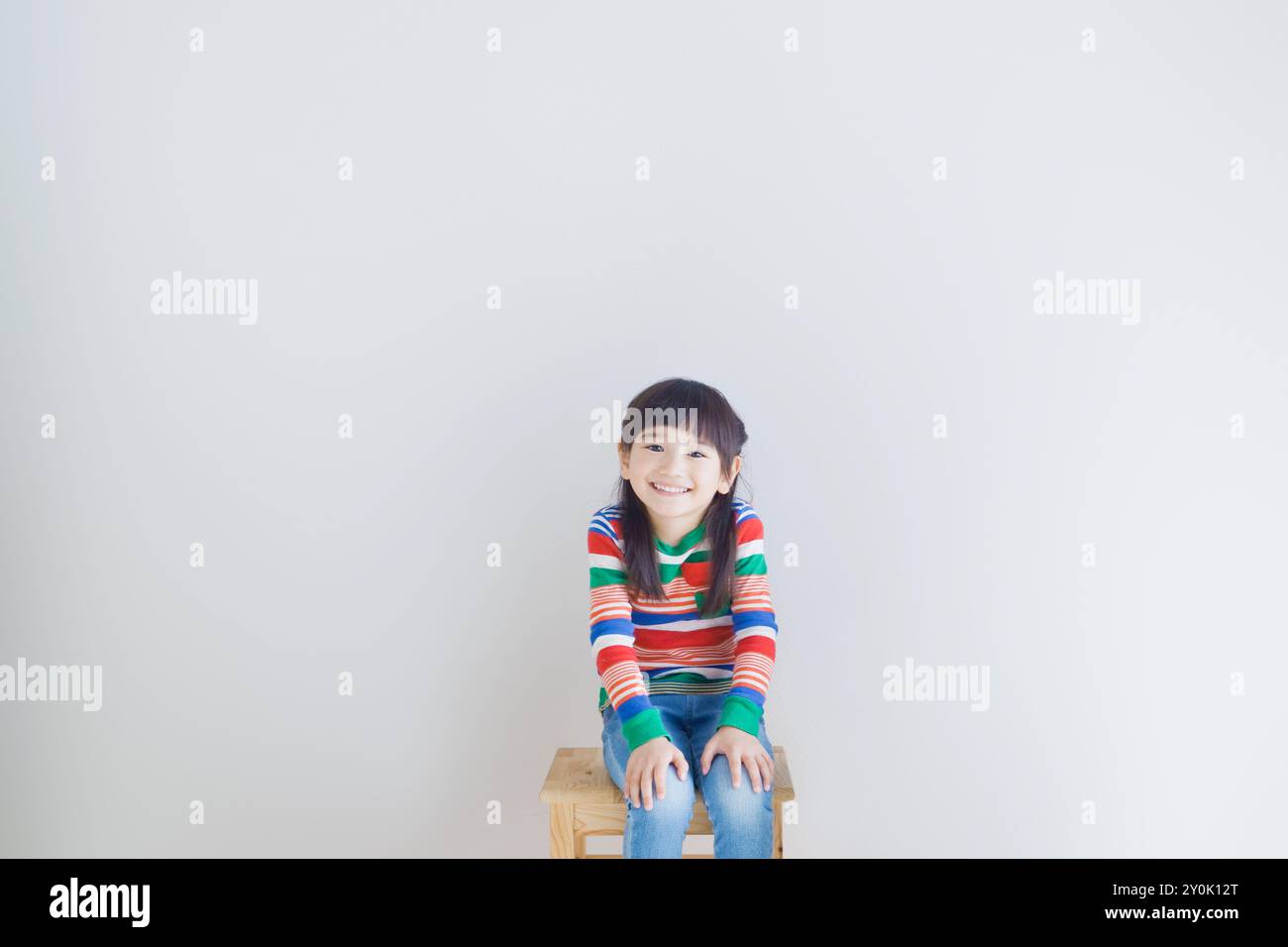 Smiling girl sitting on a chair Stock Photo - Alamy