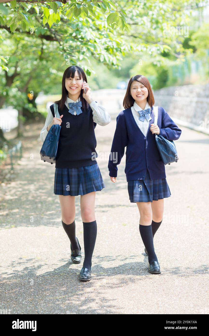 Two Japanese high school girls walking down a tree lined road Stock ...