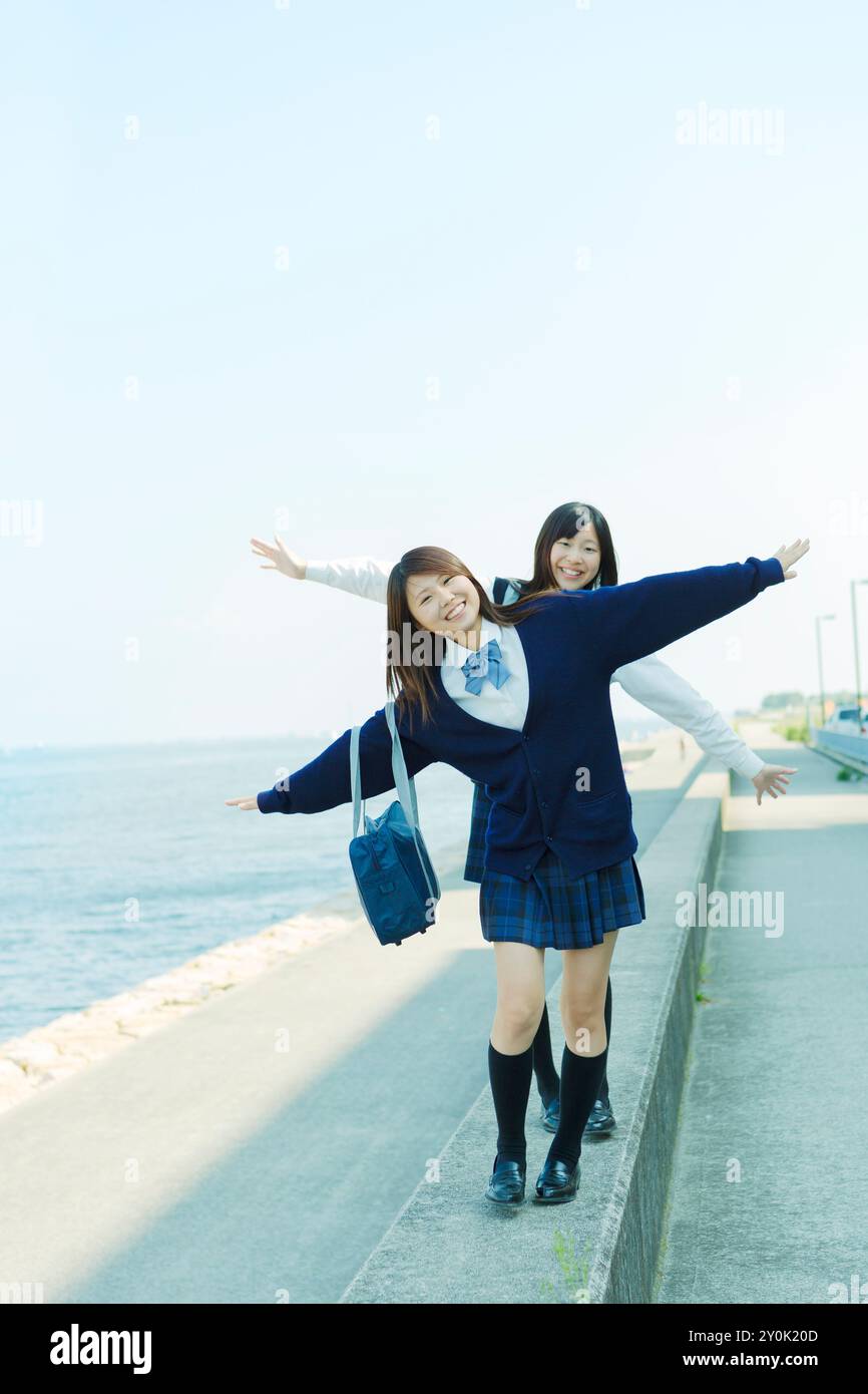 Two Japanese high school girls walking on a breakwater Stock Photo - Alamy