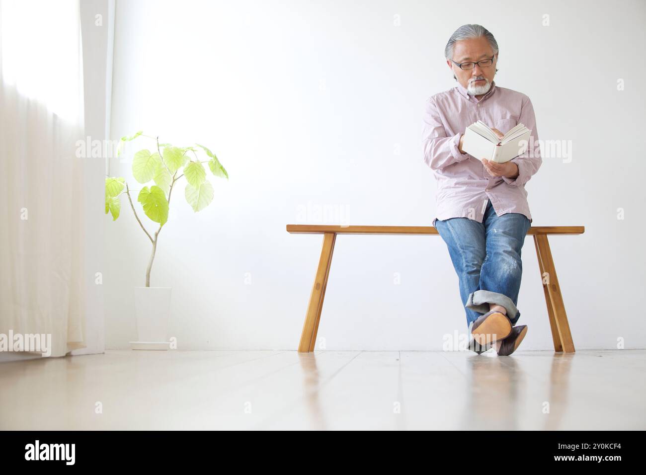 Senior man sitting on a bench and reading a book Stock Photo - Alamy