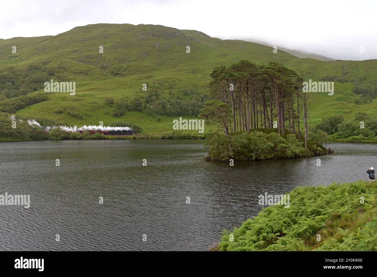 West Coat Rail preserved steam loco with The Jacobite train passing Eilean na Moine aka Dumbledores island from the Harry Potter films, July 2024 Stock Photo