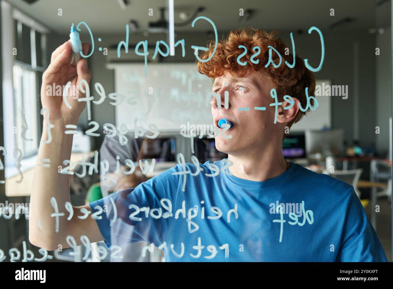 Student writing Computer Code on Glass Wall Stock Photo