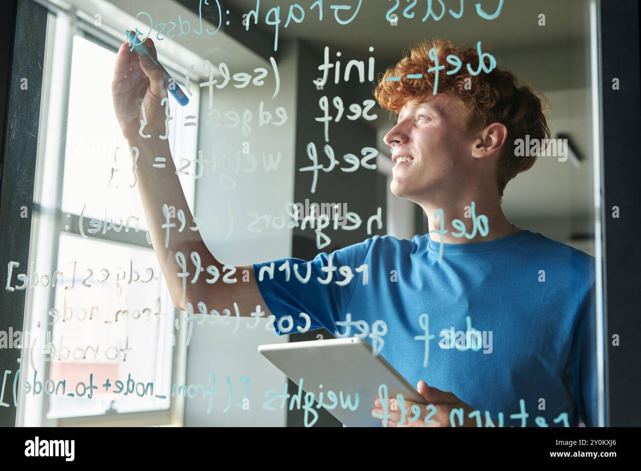 Man writing Computer Code on Glass Wall Stock Photo