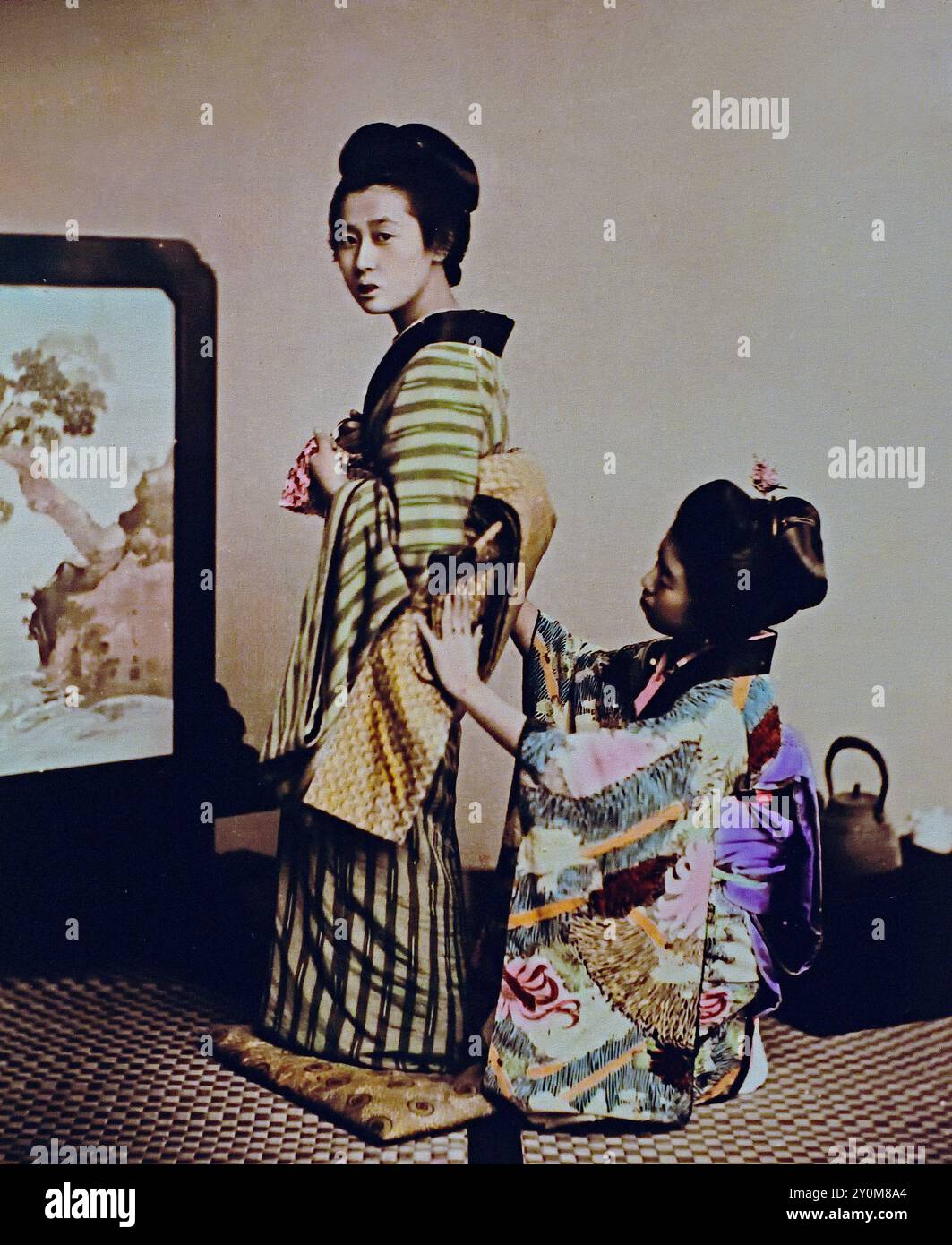 Woman being dressed 1895 By Seibei Kajima, active in the Meiji period (1868—1912). “Millionaire Photographer,” who contributed much to the world of photography in Japan.Japanese hand-coloured black and white photo Japan late 19th - beginning of 20th-century vintage albumen photograph ( Historic History ) digital improved reproduction. Stock Photo