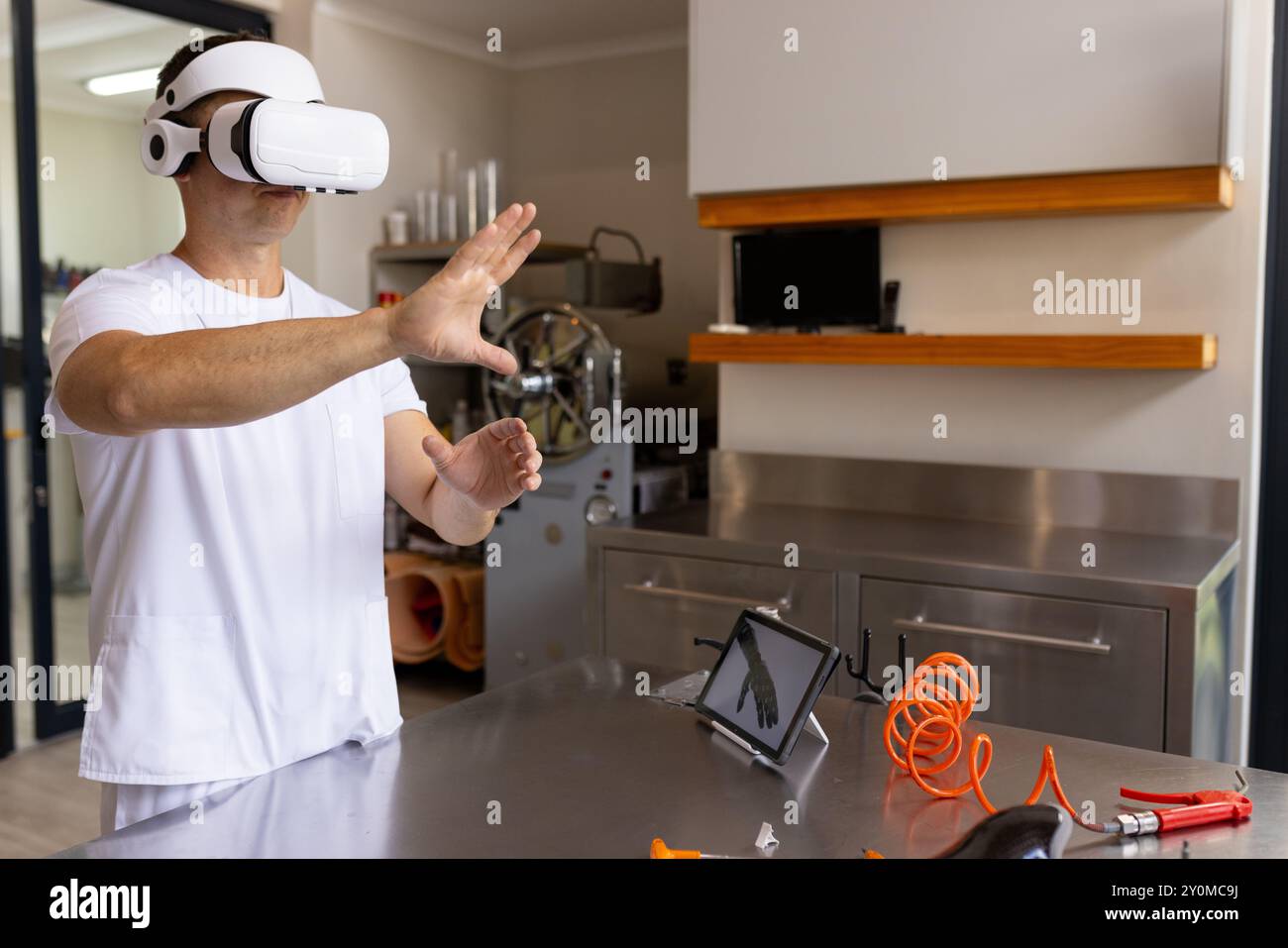 Using VR headset, technician working in prosthetic lab with tablet and tools, copy space Stock Photo