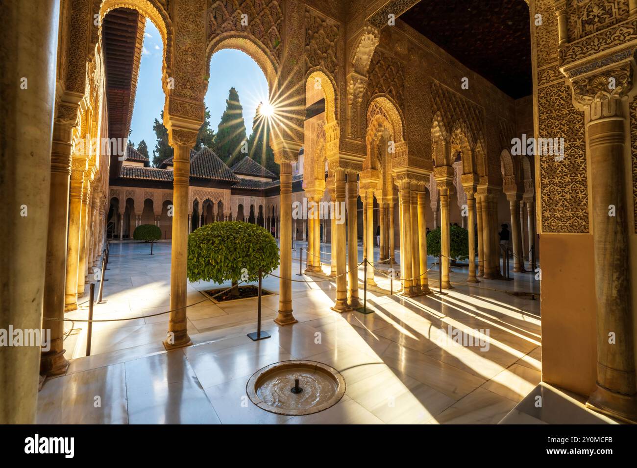 Inside Alhambra Palace, interior patio courtyard, Court of the Lions with Moorish arched pillars, columns, fountain and starburst in Granada, Spain. Stock Photo