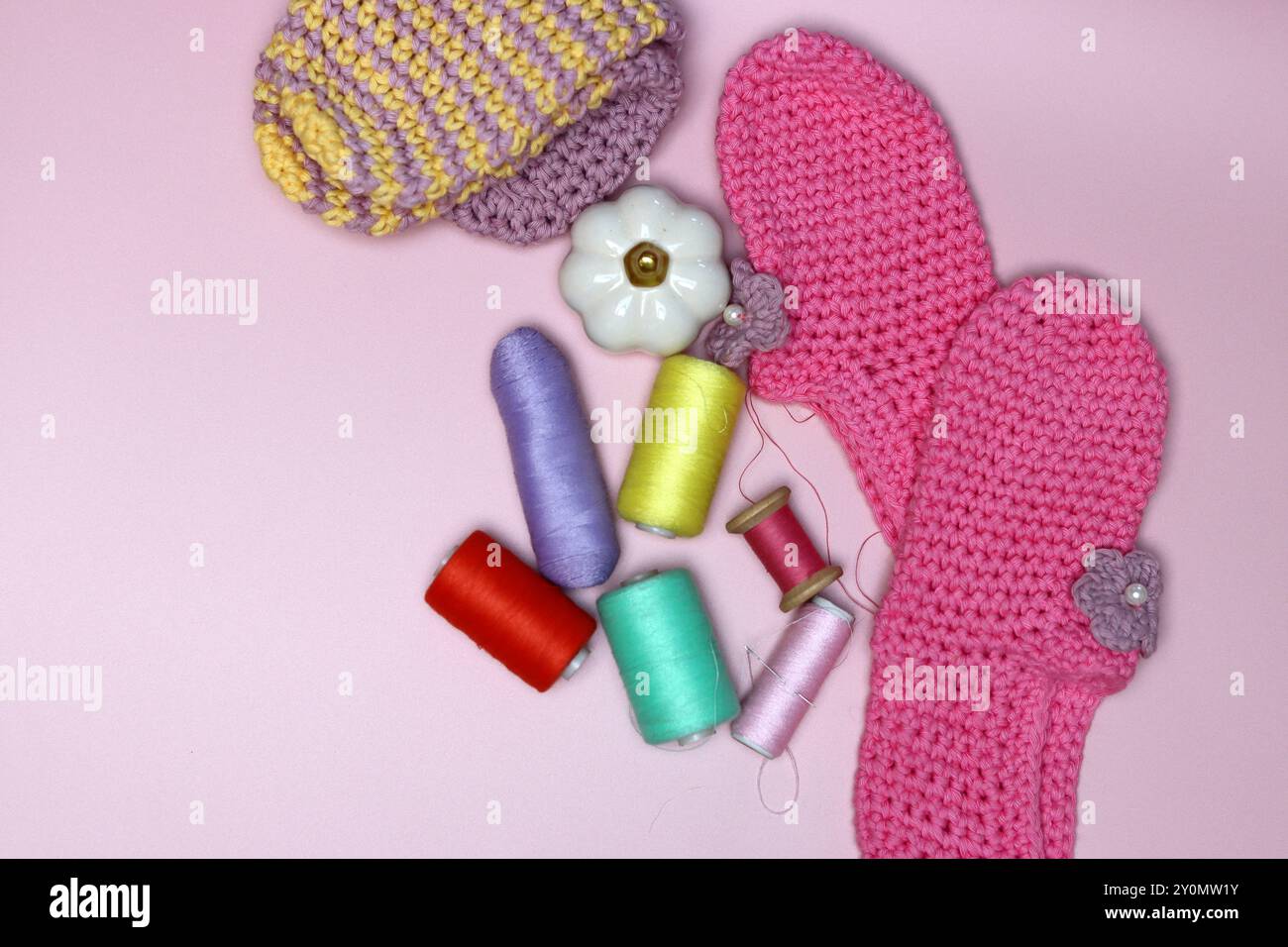 knitted clothes and accessories for needlework on a pink background. Stock Photo
