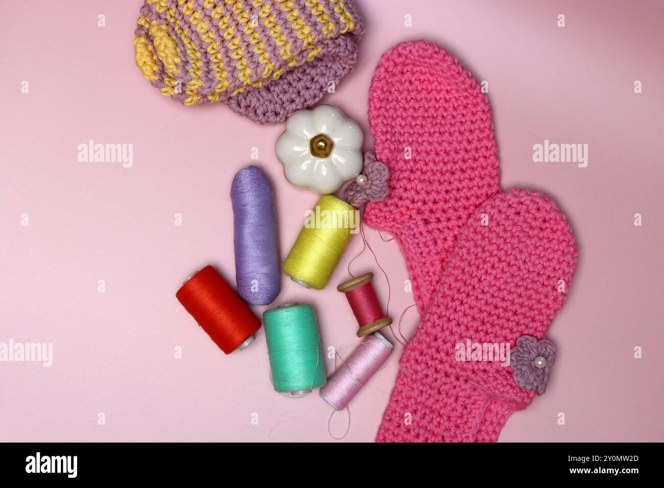 knitted clothes and accessories for needlework on a pink background. Stock Photo
