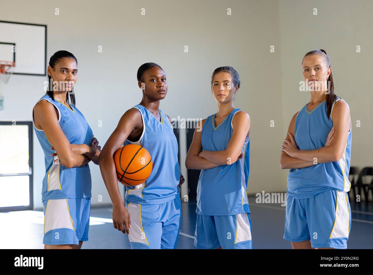 Posing confidently in gym, female basketball team holding basketball Stock Photo