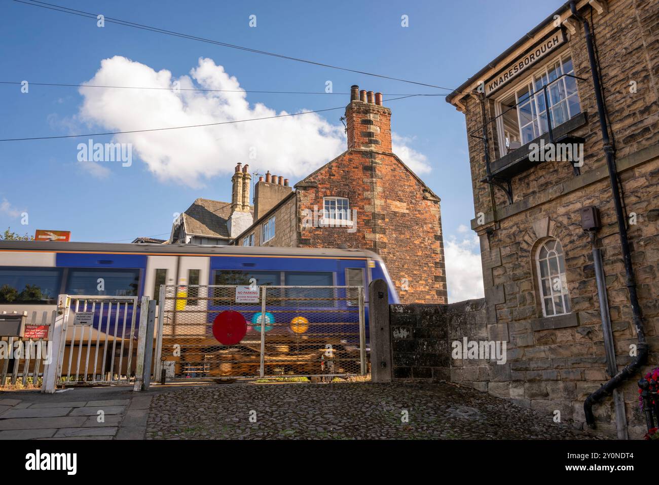 Train passing through Knaresborough Railway Station, Knaresborough, North Yorkshire, UK with signal box and crossing. Stock Photo