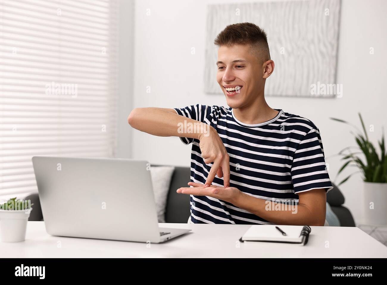 Young man using sign language during video call indoors Stock Photo