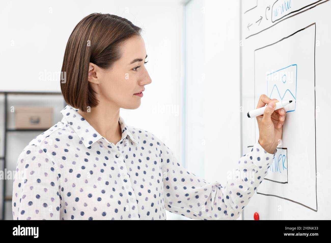 Developing UI design. Woman drawing website wireframe on whiteboard indoors Stock Photo