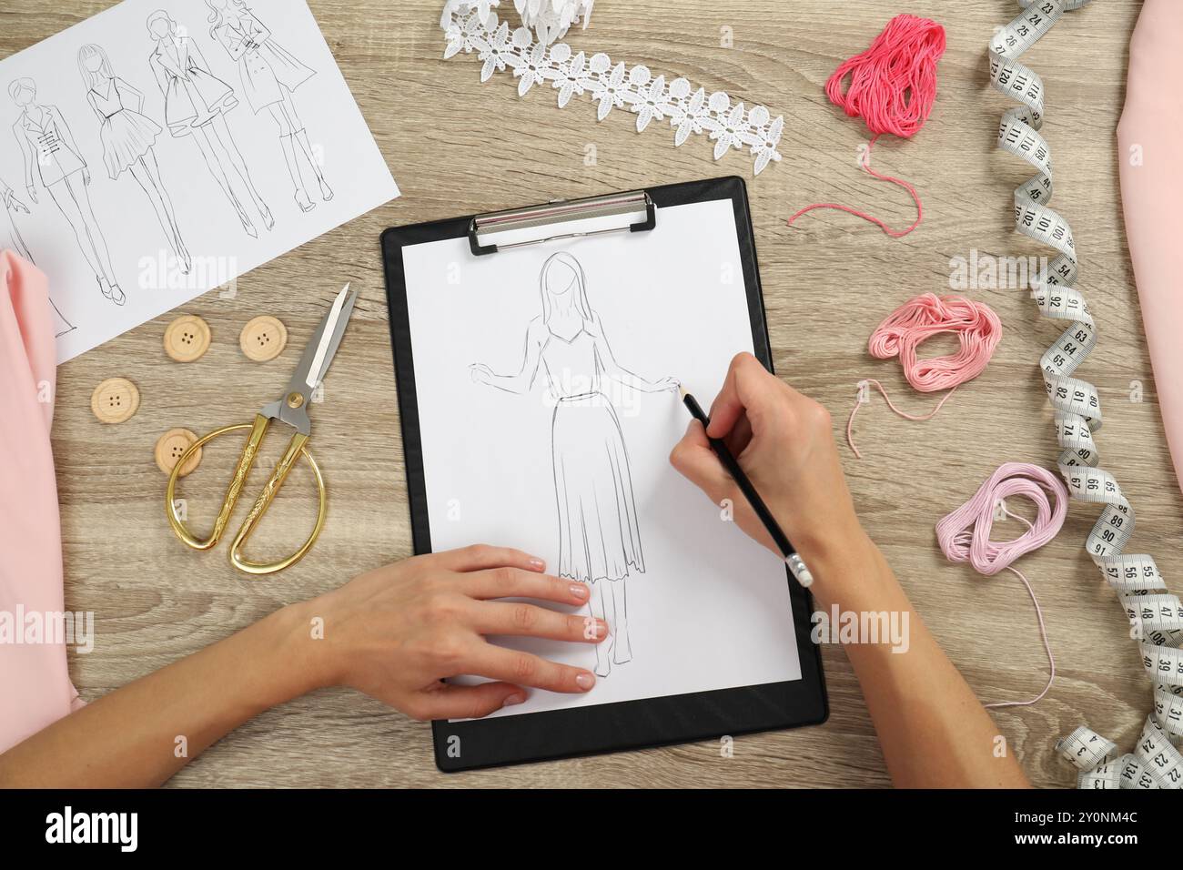 Fashion designer drawing sketch of stylish dress at wooden table, top ...