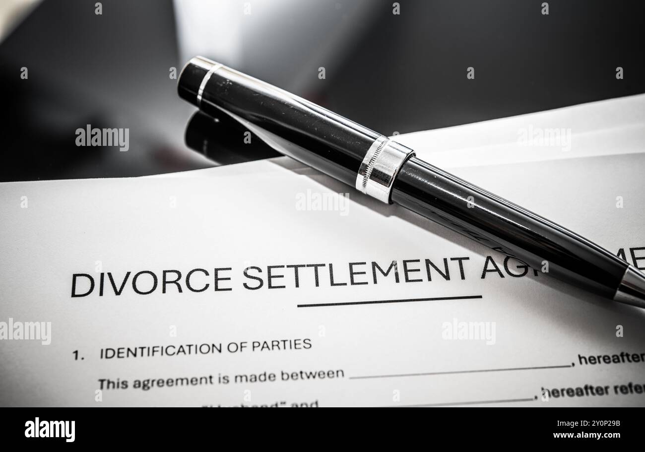 Divorce settlement agreement document on a table with a pen, representing legal separation and marital dissolution procedures for individuals seeking Stock Photo