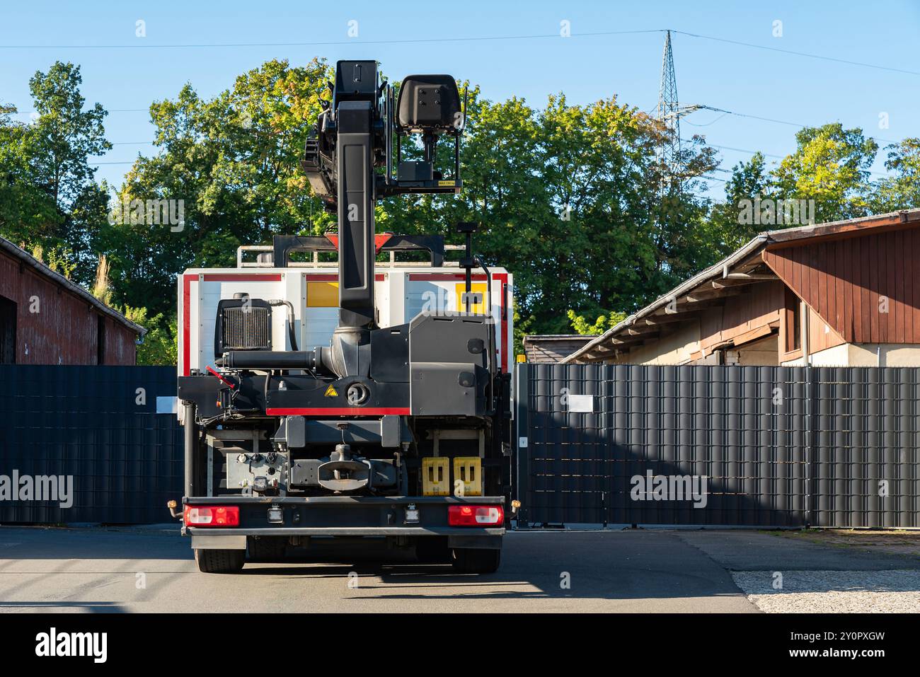 A rear view of a crane truck parked at an entrance, positioned between ...