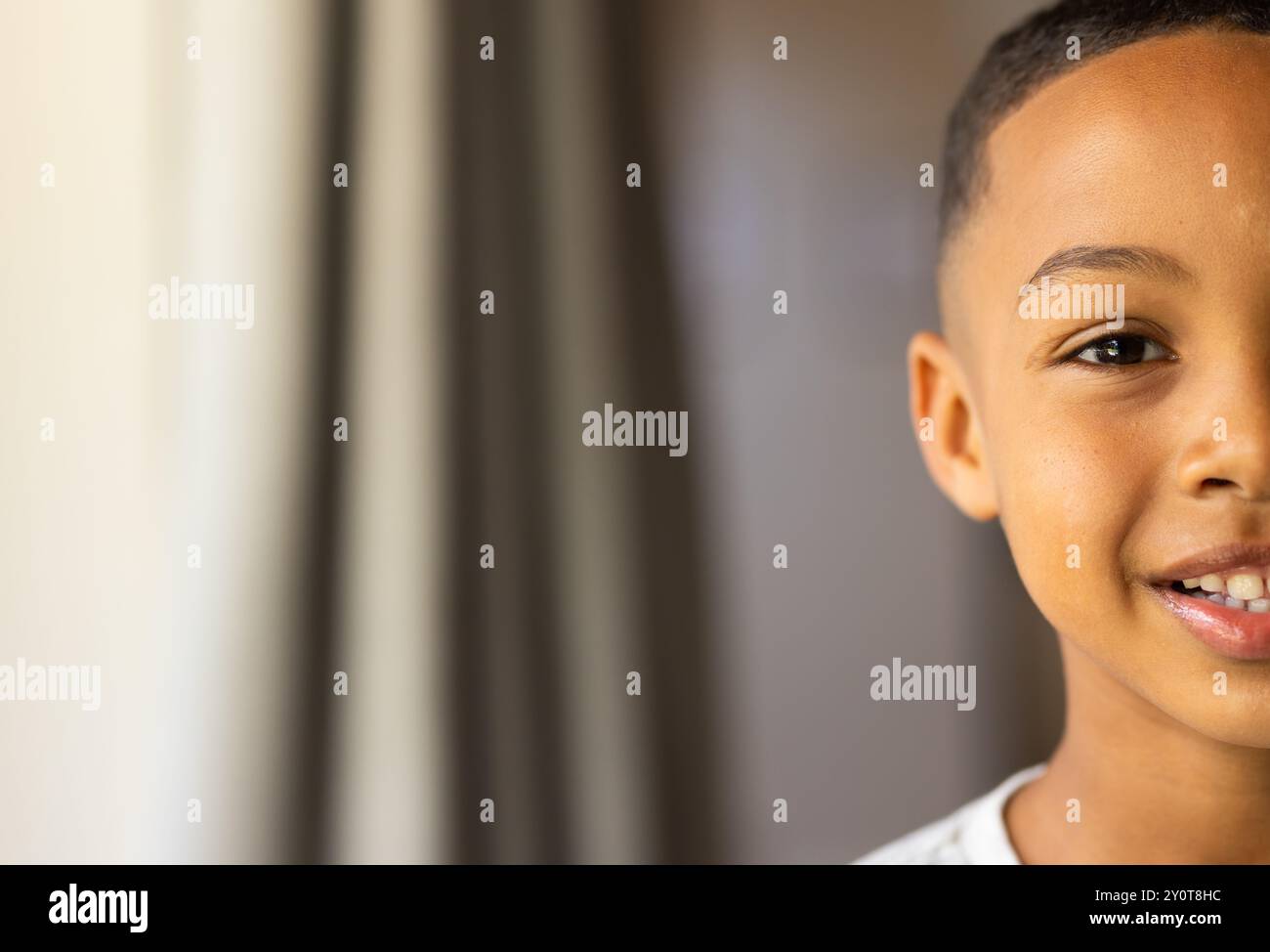 Smiling boy at home, showing half of his face, close-up portrait, copy space Stock Photo