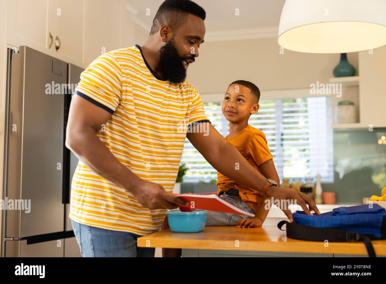 Packing lunch, father and son preparing for school in kitchen together Stock Photo