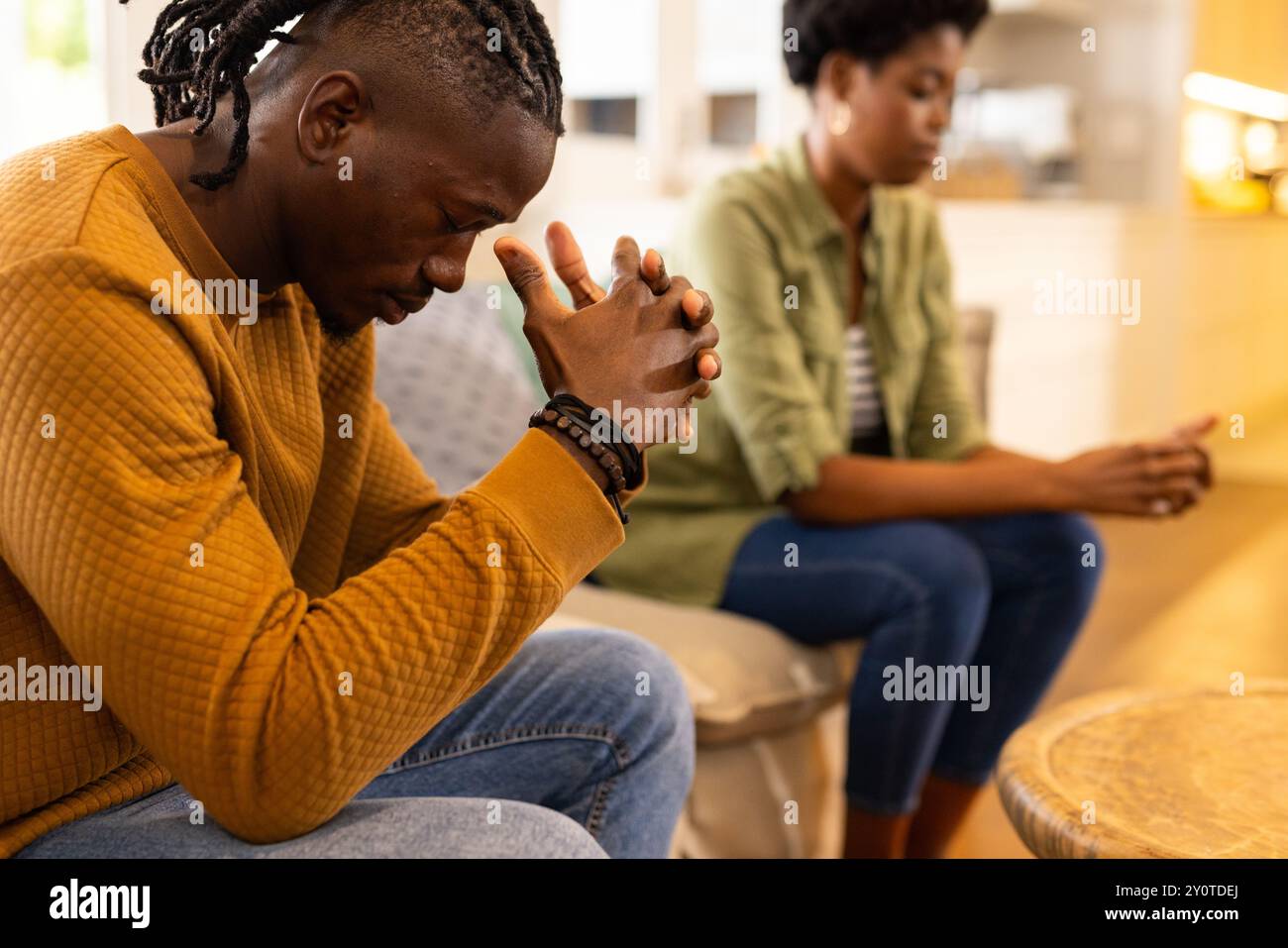 African American couple sitting on couch, deep in thought, facing away ...