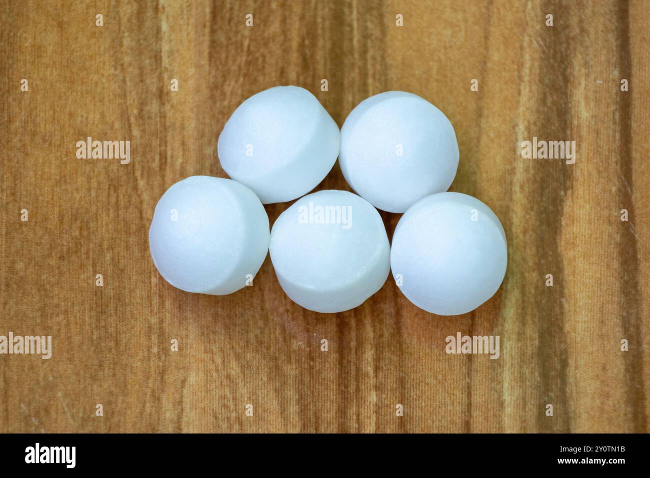 White Naphthalene mothballs isolated on wooden background. It is also ...